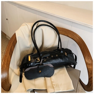 Detail of vintage oil wax leather texture and gold metal buckle on black baguette bag