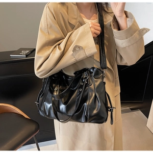 Vue détaillée du sac cabas en cuir noir brillant avec plis élégants et bandoulière chic