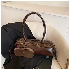 Detail of vintage dark brown faux leather shoulder bag with chic metal buckles on a white chair