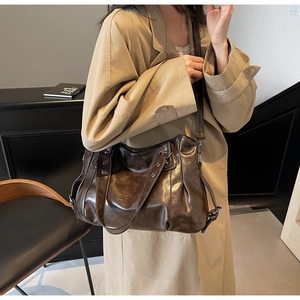 Gros plan d'un sac cabas vintage marron foncé brillant avec plis et boucle en métal au café