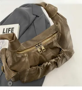 Detail of vintage brown leather bag with dual metal zippers and pleated design texture