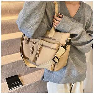 Detail view of khaki canvas tote bag featuring double front zippers and woven zipper pulls
