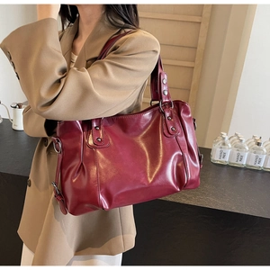 Détail du sac cabas en cuir rouge foncé avec rivets métalliques et boucles réglables