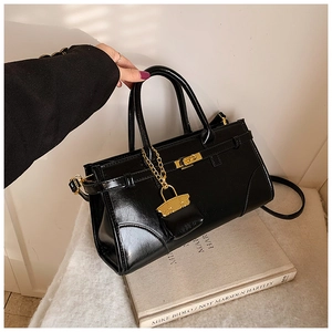 Close-up of black glossy leather briefcase with golden rotating lock and chain detail