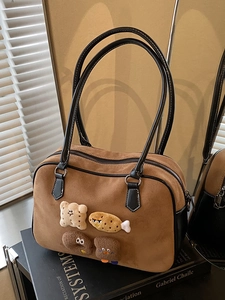 Vintage brown suede Boston bag with cartoon food patches on a stack of black books