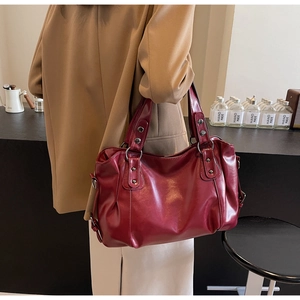 Gros plan du sac cabas en cuir bordeaux montrant la texture vintage et les rivets