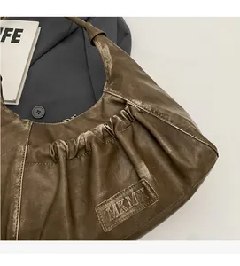 Detailed close-up of dark olive green pleated faux leather hobo bag with embossed logo