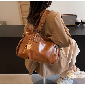 Détail du grand sac cabas vintage en cuir marron avec plis et bandoulière à rivets porté