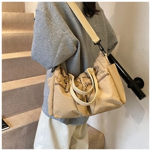 Detailed view of khaki canvas tote bag with functional zipper pockets on casual outfit