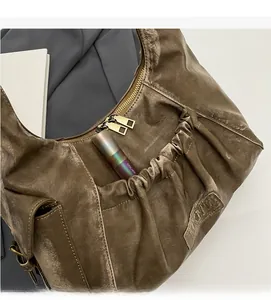 Detail shot of a brown vintage pleated hobo bag showing front pocket and metal zippers