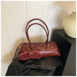 Detailed view of burgundy wax leather handbag with golden buckle and a matching pouch