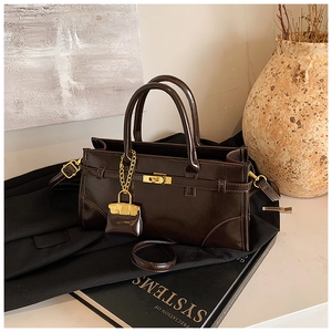 Detailed view of dark brown briefcase bag with gold lock and miniature charm accessory