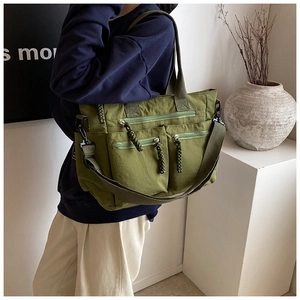 Side view of olive green multi-pocket canvas tote bag with adjustable shoulder strap