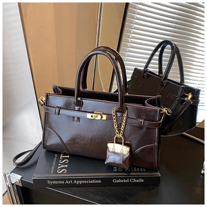 Detailed view of dark brown glossy leather handbag with gold lock and mini bag charm