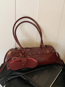 Vintage burgundy oil wax leather baguette shoulder bag with gold buckle on black book