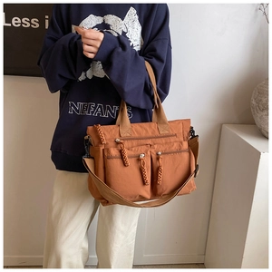 Detail of caramel brown canvas tote bag featuring front zip pockets and woven strap