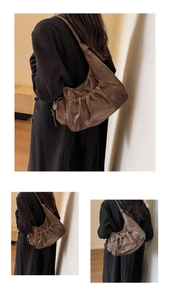 Detail shot of brown pleated hobo bag showing retro faux leather texture and MKMX logo plate