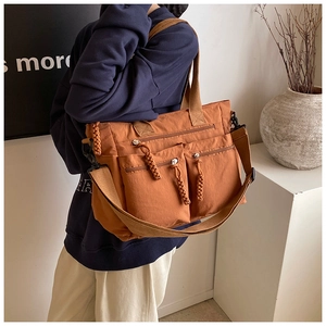 Detail of caramel tote bag showing dual front pockets and woven zipper pullers