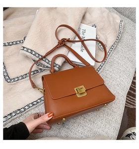 Détail du sac à main marron avec fermoir doré et pieds de protection métalliques à la base