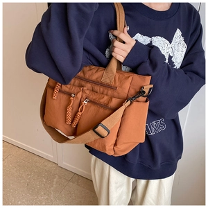 Detail view of caramel nylon tote bag with multiple zipper pockets and wide strap