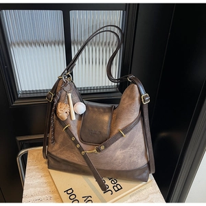 Detailed shot of vintage brown tote bag with leather flap and baseball theme keychain