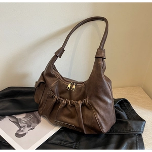 Detailed view of dark brown ruched shoulder bag with metallic double zipper and metal logo plate