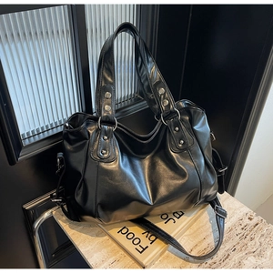 Gros plan d'un sac cabas en cuir PU noir brillant avec rivets argentés et anneaux