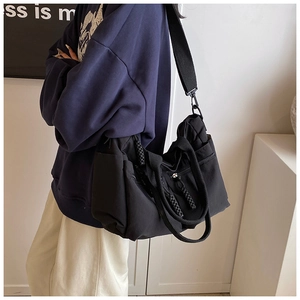 Close-up of black nylon tote bag with wide strap and side zipper pocket details