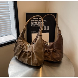 Detail of vintage pleated leather underarm bags with MKM logo embossing on a metal table
