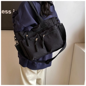 Detail view of black nylon tote bag with multi-pocket design and woven zipper pullers