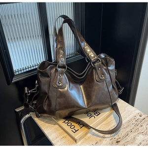 Détail d'un sac cabas vintage marron avec clous argentés sur surface en marbre
