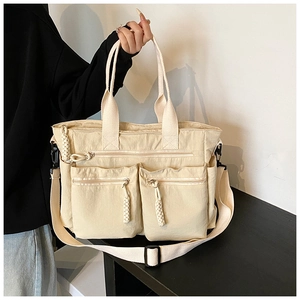 Detail of cream canvas tote bag with multiple zip pockets and adjustable shoulder strap