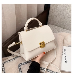 Détail d'un sac bandoulière crème en cuir texturé avec fermoir doré et poignée supérieure
