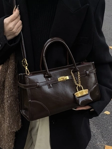 Vintage dark brown patent leather handbag with gold buckle and miniature charm accessory