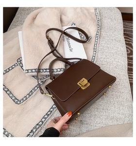 Gros plan du sac en cuir marron foncé avec fermoir rotatif en métal doré chic