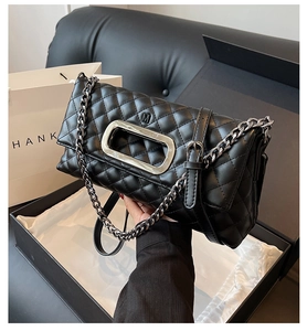 Detail der schwarzen Stepptasche mit silbernem Hohlgriff und Metallkettenriemen