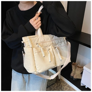 Detail of beige nylon tote bag with three front zipper pockets and textured fabric