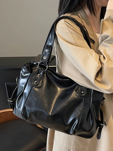 Sac fourre-tout vintage en simili cuir noir avec clous argentés porté à l'épaule du modèle