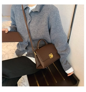 Sac à main en cuir marron avec boucle dorée porté en bandoulière sur un mannequin