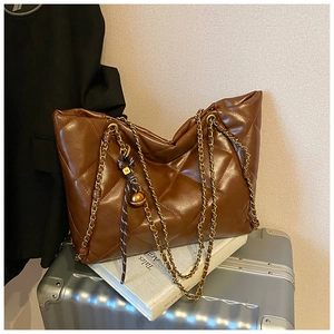 Detailed macro of brown quilted leather tote with gold chain and M-logo charm