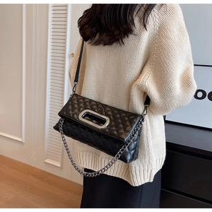 Detailansicht der gesteppten schwarzen Ledertasche mit Metallgriff und Kettendekor