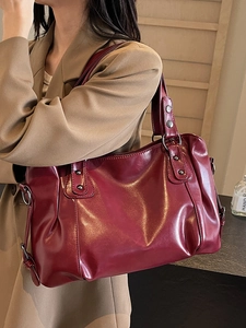 Sac fourre-tout vintage en cuir bordeaux avec rivets porté par un mannequin en manteau