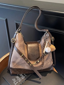 Vintage large-capacity brown tote bag with baseball charms on a wooden stool