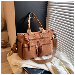 Detail of a brown nylon tote bag featuring multi-pocket design and adjustable strap