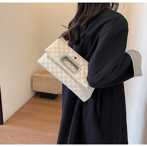 Detail der weißen gesteppten Tasche mit silbernem M-Griff und Kette auf schwarzem Mantel