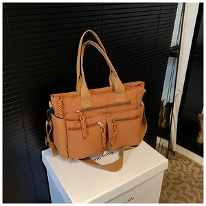 Close-up of caramel nylon tote featuring multi-pocket design and woven zipper pulls
