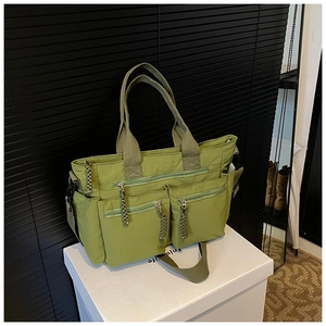 Detail view of avocado green multi-pocket tote bag with functional zippers and straps