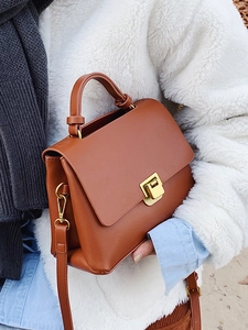 Sac à main en cuir marron avec fermoir doré sur tenue mannequin style business décontracté