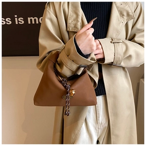 Detalle de bolso marrón en imitación de cuero con nudo trenzado y campana dorada