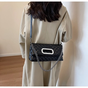 Detail der schwarzen Stepptasche mit ovaler Silberschnalle und eleganter Metallkette